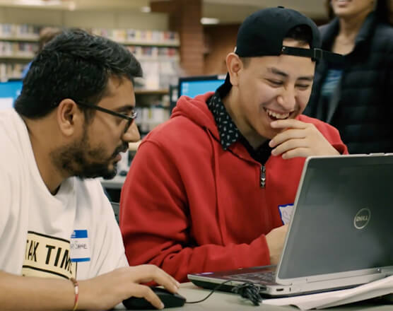 Two students laughing in front of laptop