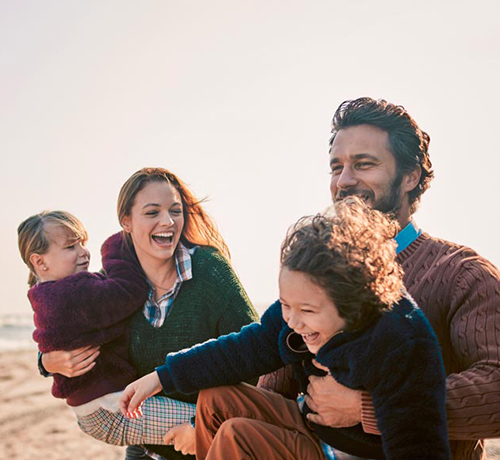 A young family on the beach, laughing. 
