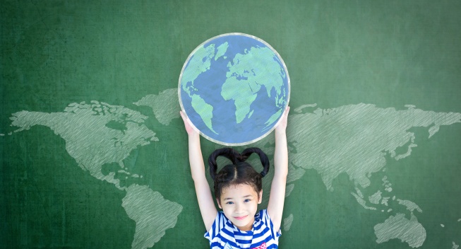 Educated school kid lifting world globe chalk doodle drawing on green chalkboard for education concept